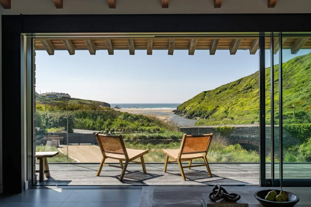The view from Noordhoek's first floor living area balcony, with two chairs looking out at Porthcothan Beach and the ocean.