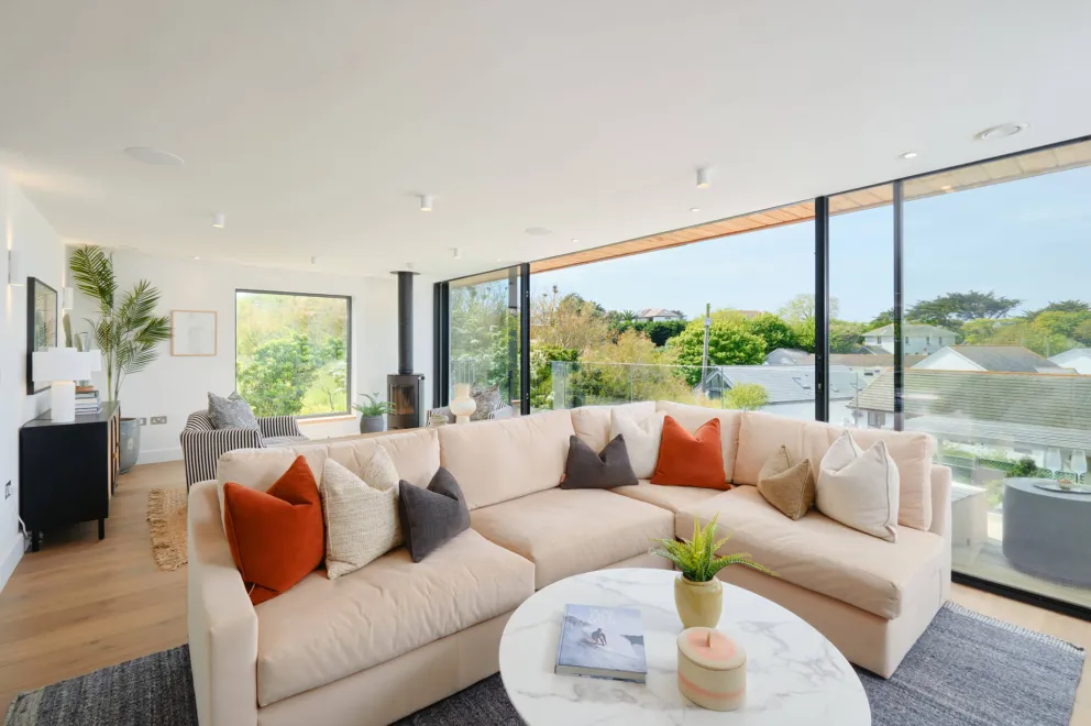 Living area with a pale pink sofa, red and blue scatter cushions and low slung coffee table.