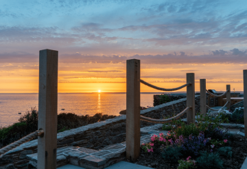 A sunset with a rope bridge in the foreground