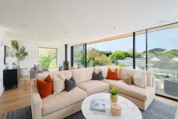 Living area with a pale pink sofa, red and blue scatter cushions and low slung coffee table.