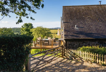 A countryside home with a balcony, covered by trees