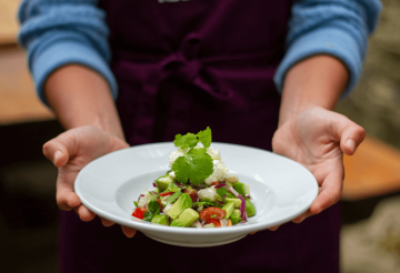 Open hands with a plate of food in the centre