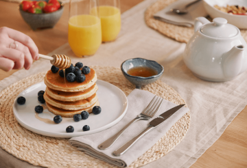 A close-up shot of pancakes, blueberries and honey on a plate