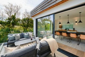 Rear balcony with two outdoor sofas and a coffee table, laid with glasses of fizz and a bowl of grapes.