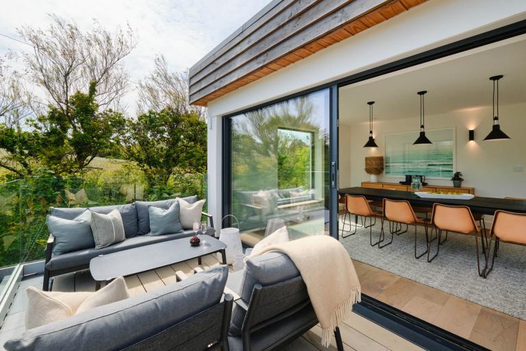 Rear balcony with two outdoor sofas and a coffee table, laid with glasses of fizz and a bowl of grapes.