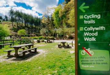 Grassy lawn with picnic benches and cycling sign in the foreground.