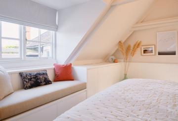 The master bedroom's window seats with orange and blue cushions.