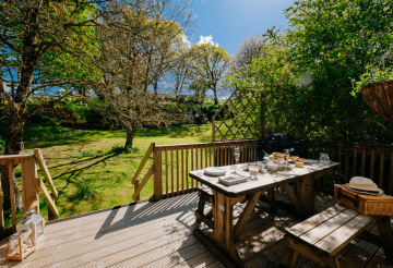 A picnic bench table on a terrace overlooking a pretty garden