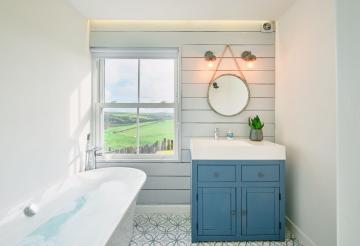 Roll top bath and round circle mirror above sink, with countryside views from the sash windows.