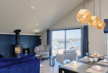 Kilden Mor's living room with blue furnishings and large window with views over the estuary.