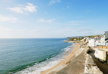 Sandy beach with lapping ocean and white houses opposite.