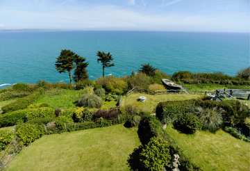 A coastal home with a large garden and the ocean in the background