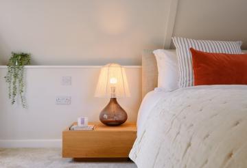 Master bedroom with bedside table and orange cushions.