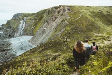 Family walking along the coast path towards Boscastle with the sea in the distance.
