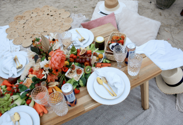 A beach picnic with table settings and flowers