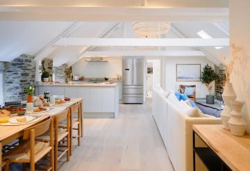 Large open-plan kitchen, dining and living area, with sloping ceilings.