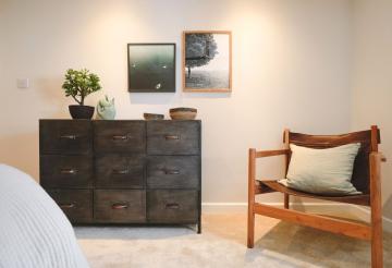 Low slung leather armchair with dark brown chest of drawers and art prints on the wall.