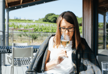 A woman sitting down with a glass of wine and a blanket