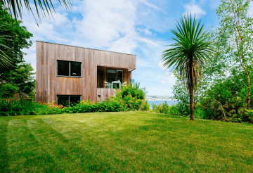 The exterior of a wood-clad home in a green garden